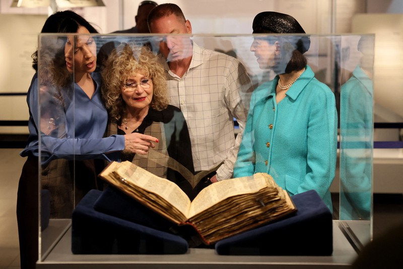 Orang-orang melihat Codex Sassoon, edisi paling awal dari Alkitab Ibrani, pada 22 Maret 2023 di Museum Orang Yahudi ANU di Tel Aviv. - Manuskrip, yang diyakini berusia lebih dari 1.000 tahun, akan dijual di lelang di New York dengan harga sekitar $50 juta. (JACK GUEZ/AFP via Getty Images)