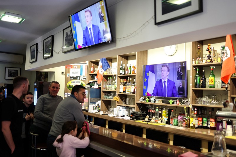 Orang-orang menonton wawancara TV Presiden Prancis Emmanuel Macron dari sebuah restoran bar di Toulouse, Prancis barat daya pada 22 Maret 2023. Orang-orang menonton wawancara TV Presiden Prancis Emmanuel Macron dari sebuah restoran bar di Toulouse, Prancis barat daya pada 22 Maret 2023. - Presiden Prancis akan membuat komentar publik pertamanya pada 22 Maret 2023 tentang krisis yang dipicu oleh pemerintahnya yang memaksakan perombakan pensiun , yang telah memicu protes keras dan pertanyaan tentang kemampuannya untuk membawa perubahan lebih lanjut. (CHARLY TRIBALLEAU/AFP via Getty Images)