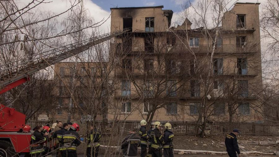 Pekerja darurat Ukraina berdiri di samping bangunan yang rusak setelah serangan pesawat tak berawak Rusia, pada 22 Maret 2023 di Rzhyshchiv, Ukraina. Pihak berwenang Ukraina mengatakan sedikitnya tujuh orang tewas ketika dua bangunan tempat tinggal dihantam oleh pasukan Rusia pada Rabu pagi. (Roman Pilipey/Getty Images)