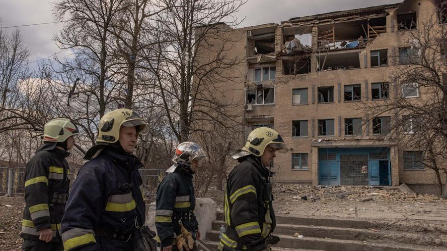 Pekerja darurat Ukraina berjalan di samping bangunan yang rusak setelah serangan pesawat tak berawak Rusia, pada 22 Maret 2023 di Rzhyshchiv, Ukraina. Pihak berwenang Ukraina mengatakan sedikitnya tujuh orang tewas ketika dua bangunan tempat tinggal dihantam oleh pasukan Rusia pada Rabu pagi. (Roman Pilipey/Getty Images)
