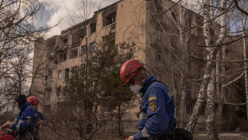 Pekerja darurat Ukraina berjalan di samping bangunan yang rusak setelah serangan pesawat tak berawak Rusia, pada 22 Maret 2023 di Rzhyshchiv, Ukraina. Pihak berwenang Ukraina mengatakan sedikitnya tujuh orang tewas ketika dua bangunan tempat tinggal dihantam oleh pasukan Rusia pada Rabu pagi. (Roman Pilipey/Getty Images)
