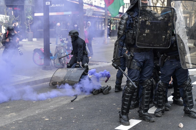 FRANCE-POLITICS-PENSIONS-DEMO Protesters run in tear gas smoke next to a street fire on the sidelines of a demonstration as part of a national day of strikes and protests, a week after the French government pushed a pensions reform through parliament without a vote, using the article 49.3 of the constitution, in Toulouse, southern France, on March 23, 2023. - French unions on March 23 staged a new day of disruption against the president's pension reform after he defiantly vowed to implement the change, which includes raising the age of retirement from 62 to 64, saying he was prepared to accept unpopularity in the face of sometimes violent protests. (Photo by Charly TRIBALLEAU / AFP)