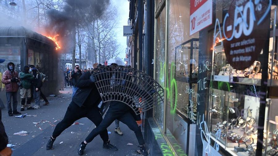 Protesters run in tear gas smoke next to   a street fire on the sidelines of a demonstration as part of a national day of strikes and protests, a week after the French government pushed a pensions reform through parliament without a vote, using the article 49.3 of the constitution, in Toulouse, southern France, on March 23, 2023. - French unions on March 23 staged a new day of disruption against the president's pension reform after he defiantly vowed to implement the change, which includes raising the age of retirement from 62 to 64, saying he was prepared to accept unpopularity in the face of sometimes violent protests. (Photo by Charly TRIBALLEAU / AFP)