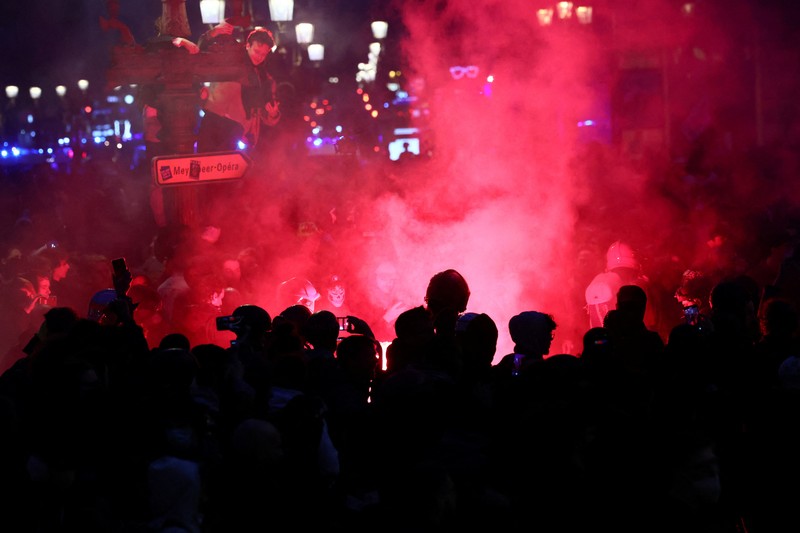 Seorang petugas polisi Prancis dengan pakaian anti huru hara berdiri di samping api selama demonstrasi di Bordeaux, Prancis (AFP via Getty Images/THIBAUD MORITZ)