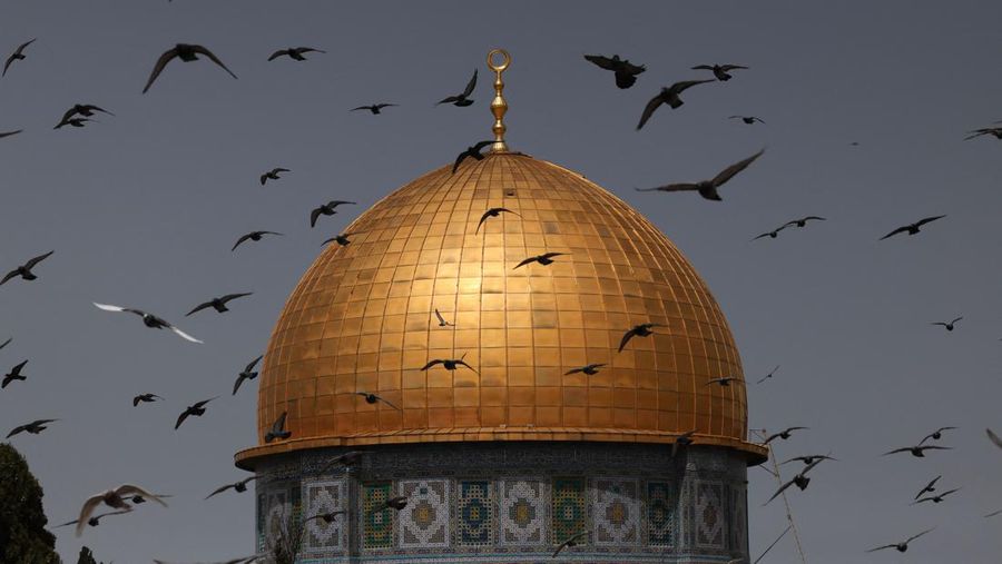 Burung terbang di depan kuil Dome of the Rock di kompleks masjid Al-Aqsa di Yerusalem, sebelum dimulainya sholat Jumat pertama bulan puasa Ramadhan, pada 24 Maret 2023. (AFP via Getty Images/AHMAD GHARABLI)