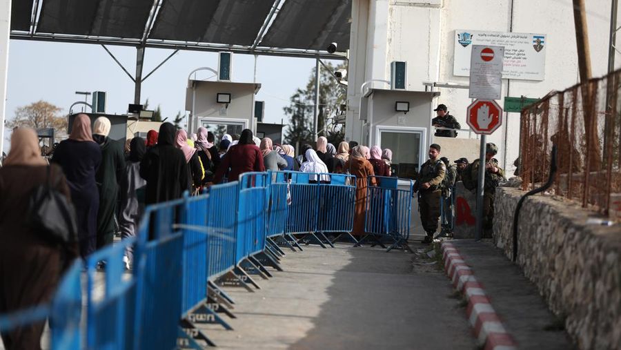Pasukan Israel mengambil langkah-langkah keamanan saat warga Palestina melewati pos pemeriksaan yang memisahkan Bethlehem dan Yerusalem, untuk menghadiri sholat Jumat pertama bulan suci Ramadhan di Masjid Al-Aqsa pada dini hari di Bethlehem. (Anadolu Agency via Getty Images)