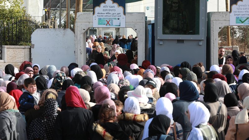 Pasukan Israel mengambil langkah-langkah keamanan saat warga Palestina melewati pos pemeriksaan yang memisahkan Bethlehem dan Yerusalem, untuk menghadiri sholat Jumat pertama bulan suci Ramadhan di Masjid Al-Aqsa pada dini hari di Bethlehem. (Anadolu Agency via Getty Images)