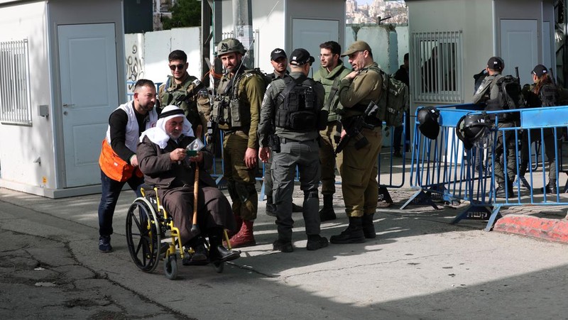 Pasukan Israel mengambil langkah-langkah keamanan saat warga Palestina melewati pos pemeriksaan yang memisahkan Bethlehem dan Yerusalem, untuk menghadiri sholat Jumat pertama bulan suci Ramadhan di Masjid Al-Aqsa pada dini hari di Bethlehem. (Anadolu Agency via Getty Images)