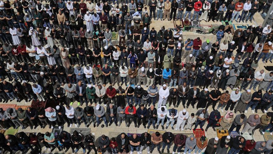 Pasukan Israel mengambil langkah-langkah keamanan saat warga Palestina melewati pos pemeriksaan yang memisahkan Bethlehem dan Yerusalem, untuk menghadiri sholat Jumat pertama bulan suci Ramadhan di Masjid Al-Aqsa pada dini hari di Bethlehem. (Anadolu Agency via Getty Images)