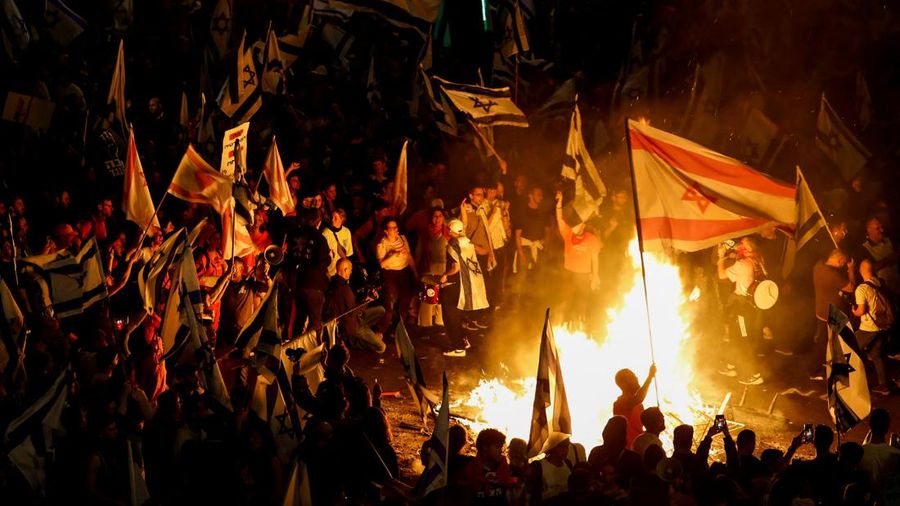 Fire burns as people attend a demonstration after Israeli Prime Minister Benjamin Netanyahu dismissed the defense minister and his nationalist coalition government presses on with its judicial overhaul, in Tel Aviv, Israel, March 27, 2023. REUTERS/Nir Elias