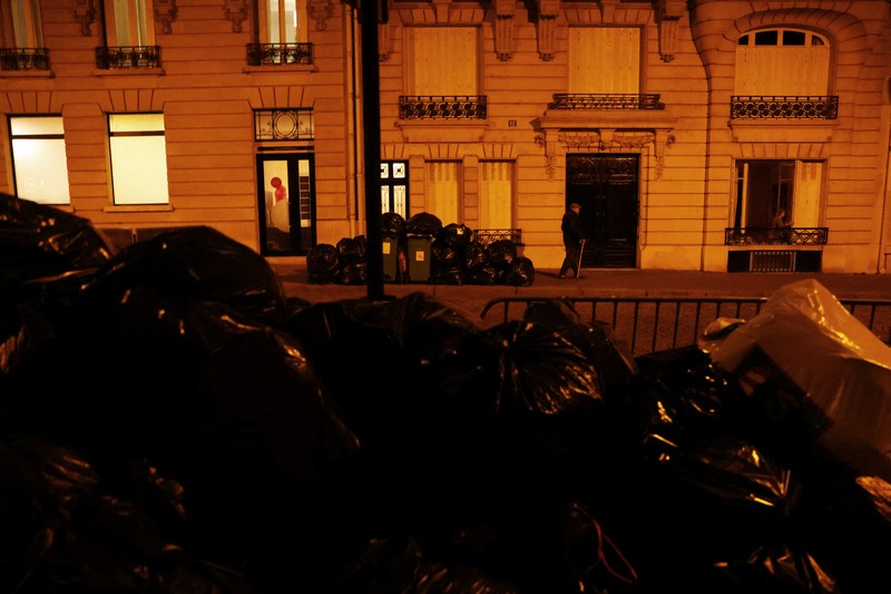 FRANCE-PENSIONS/GARBAGE Newlyweds Fabiana, 44, and Rob Burns, 53, from the U.S., pose for a photographer in front of overflowing garbage bins in a street near the Eiffel Tower as garbage has not been collected due to a strike of garbage collectors against the French government pension reform, in Paris, France, March 27, 2023. REUTERS/Nacho Doce TPX IMAGES OF THE DAY