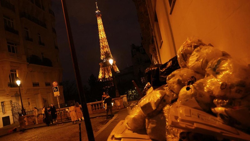 Newlyweds Fabiana, 44, and Rob Burns, 53, from the U.S., pose for a photographer in front of overflowing garbage bins in a street near the Eiffel Tower as garbage has not been collected due to a strike of garbage collectors against the French government pension reform, in Paris, France, March 27, 2023. REUTERS/Nacho Doce     TPX IMAGES OF THE DAY