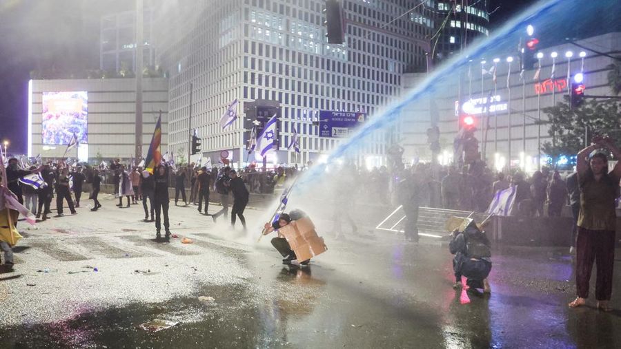 Israeli protesters react as a water cannon is used to disperse the people attending a demonstration against Israeli Prime Minister Benjamin Netanyahu and his nationalist coalition government's plan for judicial overhaul, in Tel Aviv, Israel, March 27, 2023. REUTERS/Itai Ron  NO RESALES. NO ARCHIVES