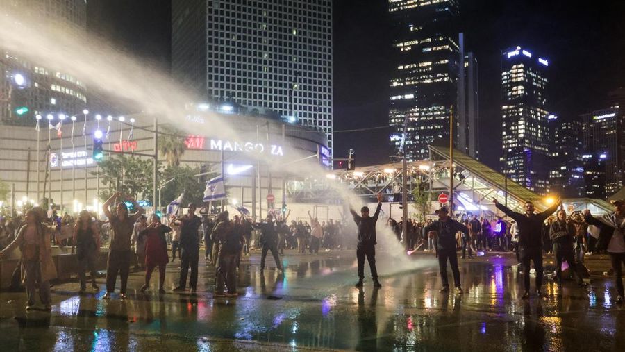 Israeli protesters react as a water cannon is used to disperse the people attending a demonstration against Israeli Prime Minister Benjamin Netanyahu and his nationalist coalition government's plan for judicial overhaul, in Tel Aviv, Israel, March 27, 2023. REUTERS/Itai Ron  NO RESALES. NO ARCHIVES