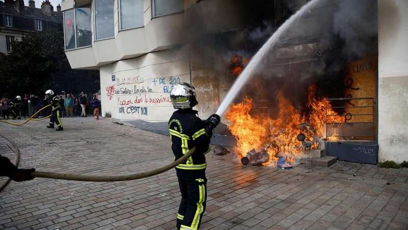 French firefighters try to extinguish a burning BNP Paribas bank office during clashes at a demonstration as part of the tenth day of nationwide strikes and protests against French government's pension reform in Nantes, France, March 28, 2023.   REUTERS/Stephane Mahe