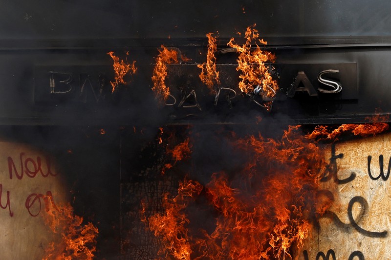 French firefighters try to extinguish a burning BNP Paribas bank office during clashes at a demonstration as part of the tenth day of nationwide strikes and protests against French government's pension reform in Nantes, France, March 28, 2023.   REUTERS/Stephane Mahe