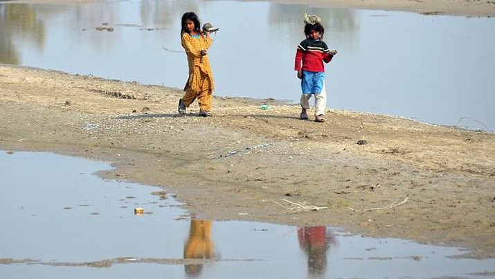 Pakistan Internally displaced flood-affected girls walk beside the flood waters near a makeshift camp in the flood-hit area of Dera Allah Yar in Jaffarabad district of Balochistan province on January 9, 2023. - The UN chief called on January 9 for