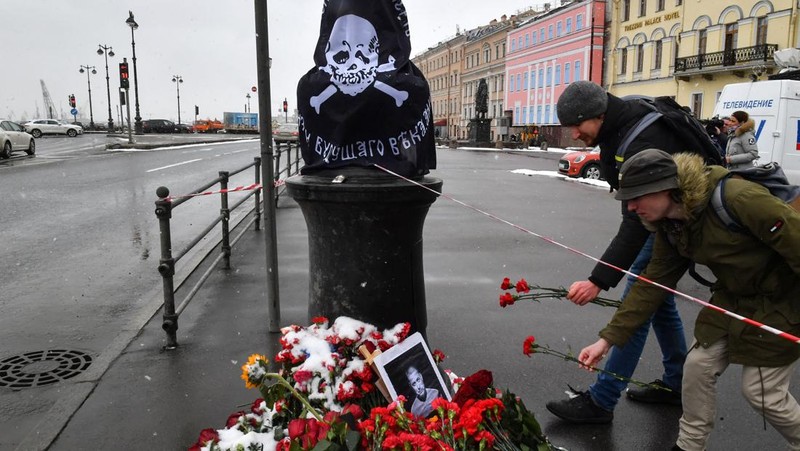 Para pria meletakkan bunga di tugu peringatan darurat untuk blogger militer Rusia Vladlen Tatarsky, yang bernama asli Maxim Fomin, yang tewas dalam ledakan bom 2 April di sebuah kafe, di lokasi ledakan di Saint Petersburg pada 3 April 2023. (OLGA MALTSEVA/AFP via Getty Images)