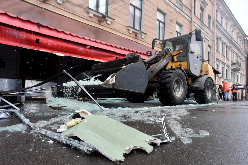 Para pria meletakkan bunga di tugu peringatan darurat untuk blogger militer Rusia Vladlen Tatarsky, yang bernama asli Maxim Fomin, yang tewas dalam ledakan bom 2 April di sebuah kafe, di lokasi ledakan di Saint Petersburg pada 3 April 2023. (OLGA MALTSEVA/AFP via Getty Images)