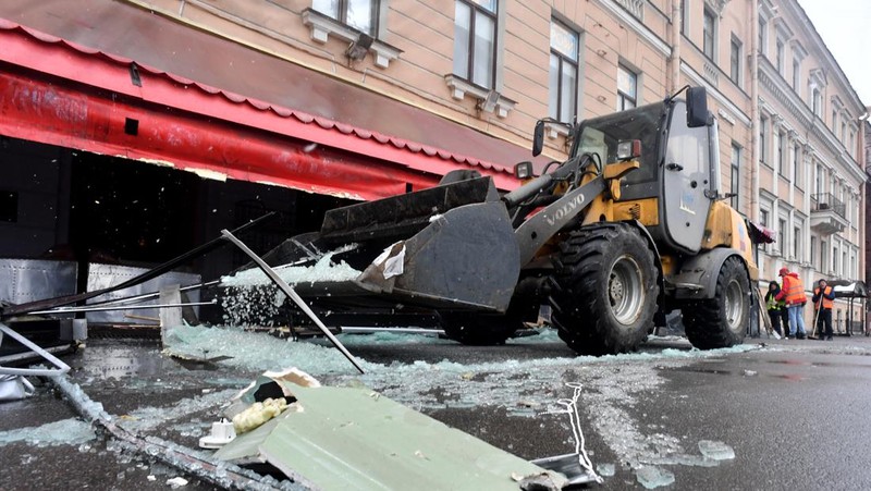 Para pria meletakkan bunga di tugu peringatan darurat untuk blogger militer Rusia Vladlen Tatarsky, yang bernama asli Maxim Fomin, yang tewas dalam ledakan bom 2 April di sebuah kafe, di lokasi ledakan di Saint Petersburg pada 3 April 2023. (OLGA MALTSEVA/AFP via Getty Images)