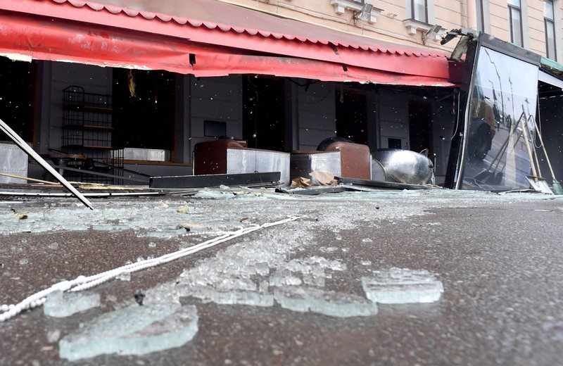 Para pria meletakkan bunga di tugu peringatan darurat untuk blogger militer Rusia Vladlen Tatarsky, yang bernama asli Maxim Fomin, yang tewas dalam ledakan bom 2 April di sebuah kafe, di lokasi ledakan di Saint Petersburg pada 3 April 2023. (OLGA MALTSEVA/AFP via Getty Images)