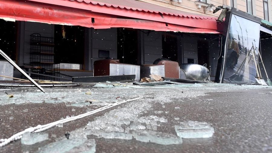 Para pria meletakkan bunga di tugu peringatan darurat untuk blogger militer Rusia Vladlen Tatarsky, yang bernama asli Maxim Fomin, yang tewas dalam ledakan bom 2 April di sebuah kafe, di lokasi ledakan di Saint Petersburg pada 3 April 2023. (OLGA MALTSEVA/AFP via Getty Images)