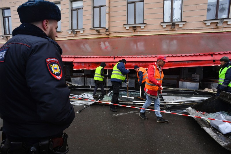Para pria meletakkan bunga di tugu peringatan darurat untuk blogger militer Rusia Vladlen Tatarsky, yang bernama asli Maxim Fomin, yang tewas dalam ledakan bom 2 April di sebuah kafe, di lokasi ledakan di Saint Petersburg pada 3 April 2023. (OLGA MALTSEVA/AFP via Getty Images)