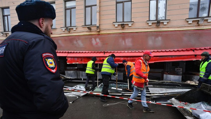 Para pria meletakkan bunga di tugu peringatan darurat untuk blogger militer Rusia Vladlen Tatarsky, yang bernama asli Maxim Fomin, yang tewas dalam ledakan bom 2 April di sebuah kafe, di lokasi ledakan di Saint Petersburg pada 3 April 2023. (OLGA MALTSEVA/AFP via Getty Images)