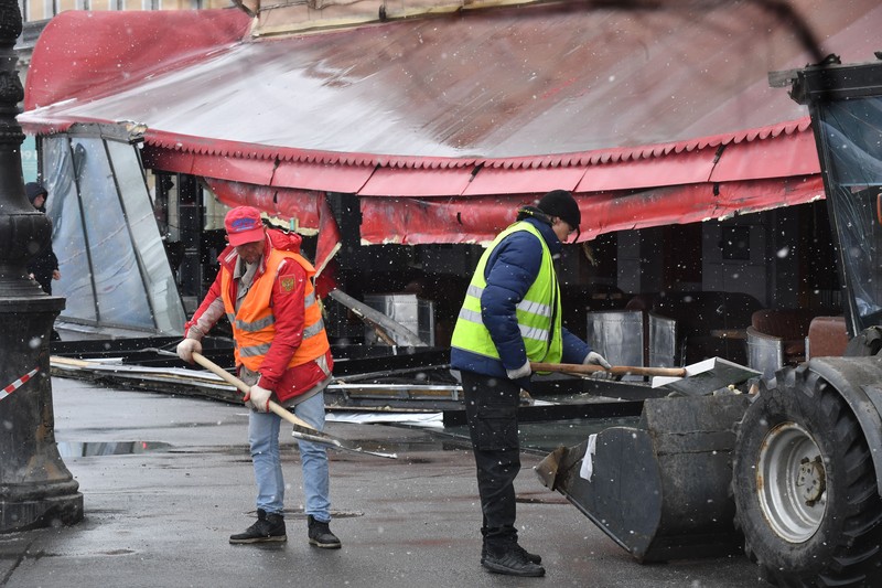 Para pria meletakkan bunga di tugu peringatan darurat untuk blogger militer Rusia Vladlen Tatarsky, yang bernama asli Maxim Fomin, yang tewas dalam ledakan bom 2 April di sebuah kafe, di lokasi ledakan di Saint Petersburg pada 3 April 2023. (OLGA MALTSEVA/AFP via Getty Images)