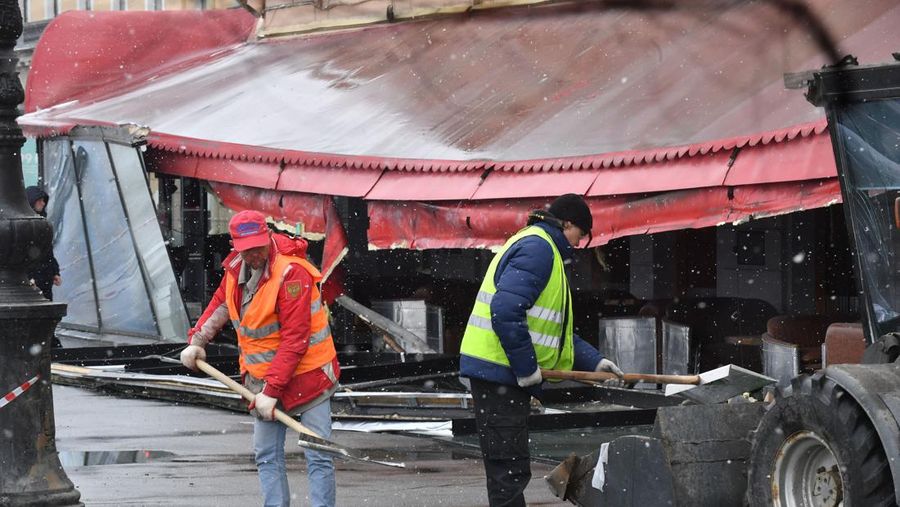 Para pria meletakkan bunga di tugu peringatan darurat untuk blogger militer Rusia Vladlen Tatarsky, yang bernama asli Maxim Fomin, yang tewas dalam ledakan bom 2 April di sebuah kafe, di lokasi ledakan di Saint Petersburg pada 3 April 2023. (OLGA MALTSEVA/AFP via Getty Images)
