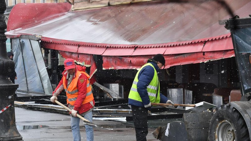Para pria meletakkan bunga di tugu peringatan darurat untuk blogger militer Rusia Vladlen Tatarsky, yang bernama asli Maxim Fomin, yang tewas dalam ledakan bom 2 April di sebuah kafe, di lokasi ledakan di Saint Petersburg pada 3 April 2023. (OLGA MALTSEVA/AFP via Getty Images)