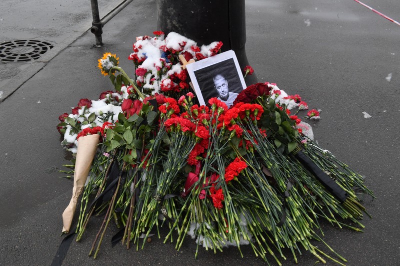 Para pria meletakkan bunga di tugu peringatan darurat untuk blogger militer Rusia Vladlen Tatarsky, yang bernama asli Maxim Fomin, yang tewas dalam ledakan bom 2 April di sebuah kafe, di lokasi ledakan di Saint Petersburg pada 3 April 2023. (OLGA MALTSEVA/AFP via Getty Images)