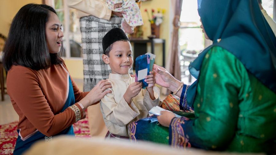Young boy being presented with a gift of money from his grandparents as part of the Islamic celebration of Hari Raya Aidilfitri (Eid al-Fitr). Kuala Lumpur, Malaysia. May 2018