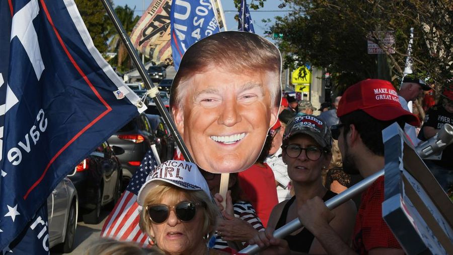 Pendukung mantan Presiden AS Donald Trump melambai-lambaikan tanda dan bendera saat mereka menunggu iring-iringan yang membawa Trump untuk kembali ke Mar-a-Lago Club setelah dakwaannya di New York pada 4 April 2023 di West Palm Beach, Florida. (Paul Hennessy/Anadolu Agency via Getty Images)