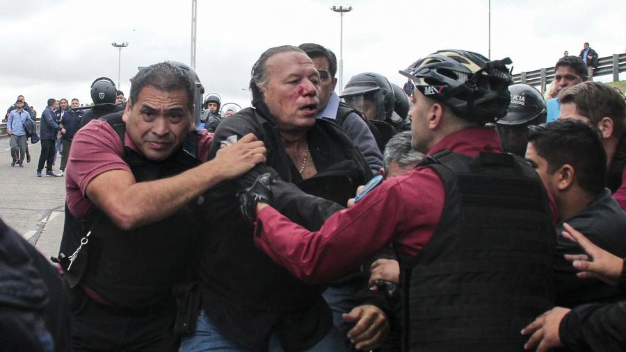 Menteri Keamanan provinsi Buenos Aires, Sergio Berni dilindungi oleh polisi dilindungi setelah dipukuli oleh sekelompok pengemudi bus yang memprotes pembunuhan seorang rekannya di La Matanza, Buenos Aires, (3/4/2023). (AFP via Getty Images/ANDRES PELOZO)