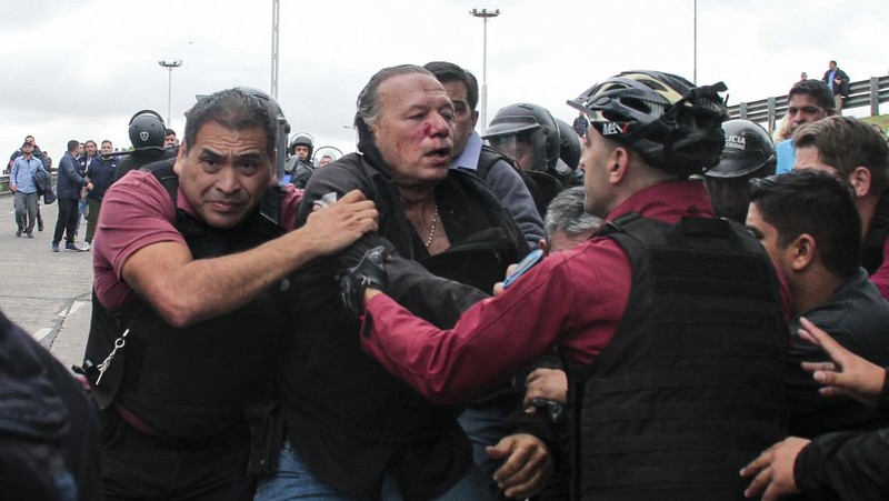 Menteri Keamanan provinsi Buenos Aires, Sergio Berni dilindungi oleh polisi dilindungi setelah dipukuli oleh sekelompok pengemudi bus yang memprotes pembunuhan seorang rekannya di La Matanza, Buenos Aires, (3/4/2023). (AFP via Getty Images/ANDRES PELOZO)