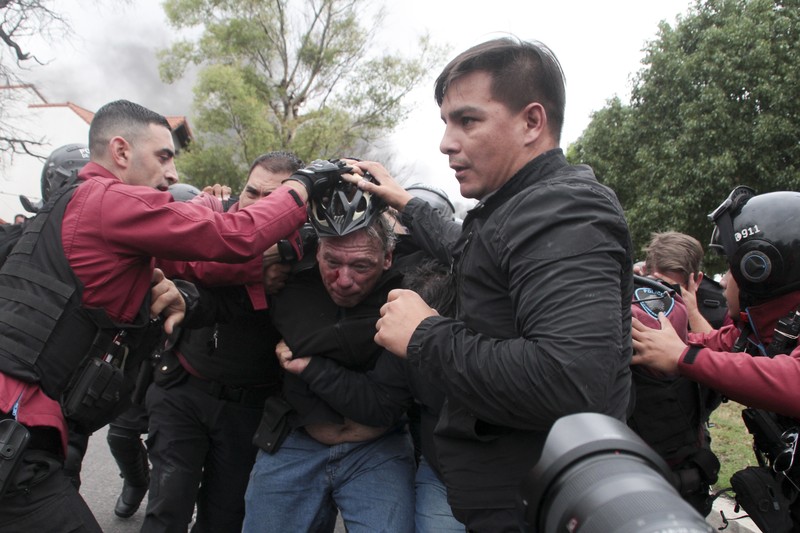 Menteri Keamanan provinsi Buenos Aires, Sergio Berni dilindungi oleh polisi dilindungi setelah dipukuli oleh sekelompok pengemudi bus yang memprotes pembunuhan seorang rekannya di La Matanza, Buenos Aires, (3/4/2023). (AFP via Getty Images/ANDRES PELOZO)