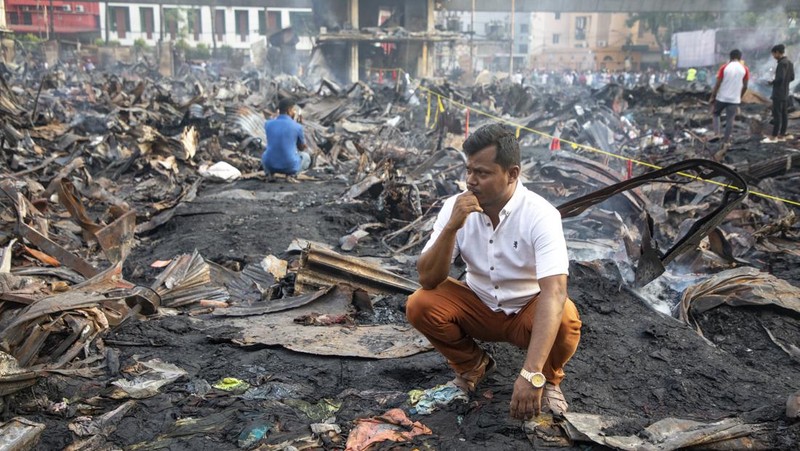 Pedagang korban kebakaran mencari barang dagangan, uang, dan barang berharga lainnya sementara asap terus mengepul dari reruntuhan yang hangus pada hari Rabu setelah kebakaran melanda kompleks perbelanjaan Bangabazar yang menampung beberapa ribu toko di Phulbariai Dhaka pada 05 April 2023. (Sony Ramany/NurPhoto via Getty Images)