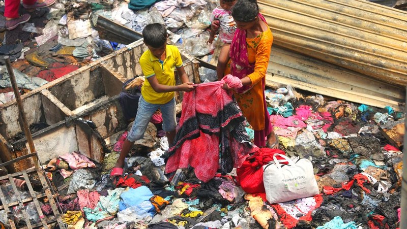 Pedagang korban kebakaran mencari barang dagangan, uang, dan barang berharga lainnya sementara asap terus mengepul dari reruntuhan yang hangus pada hari Rabu setelah kebakaran melanda kompleks perbelanjaan Bangabazar yang menampung beberapa ribu toko di Phulbariai Dhaka pada 05 April 2023. (Sony Ramany/NurPhoto via Getty Images)