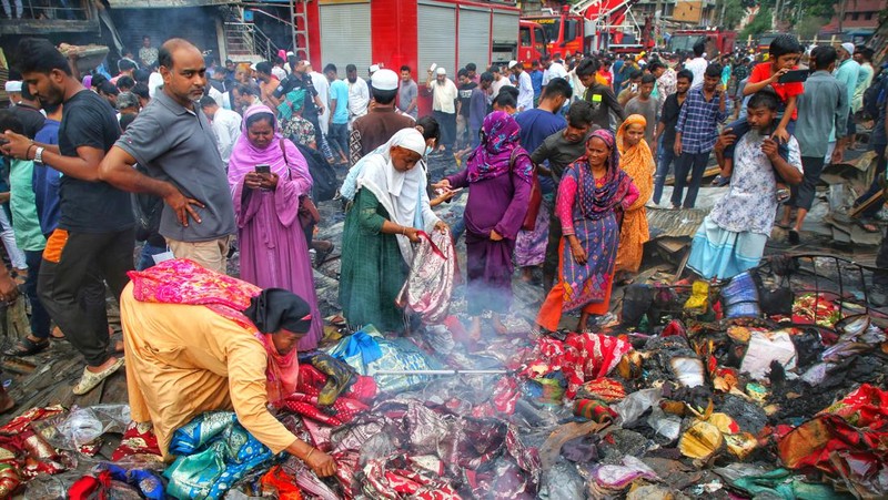 Pedagang korban kebakaran mencari barang dagangan, uang, dan barang berharga lainnya sementara asap terus mengepul dari reruntuhan yang hangus pada hari Rabu setelah kebakaran melanda kompleks perbelanjaan Bangabazar yang menampung beberapa ribu toko di Phulbariai Dhaka pada 05 April 2023. (Sony Ramany/NurPhoto via Getty Images)