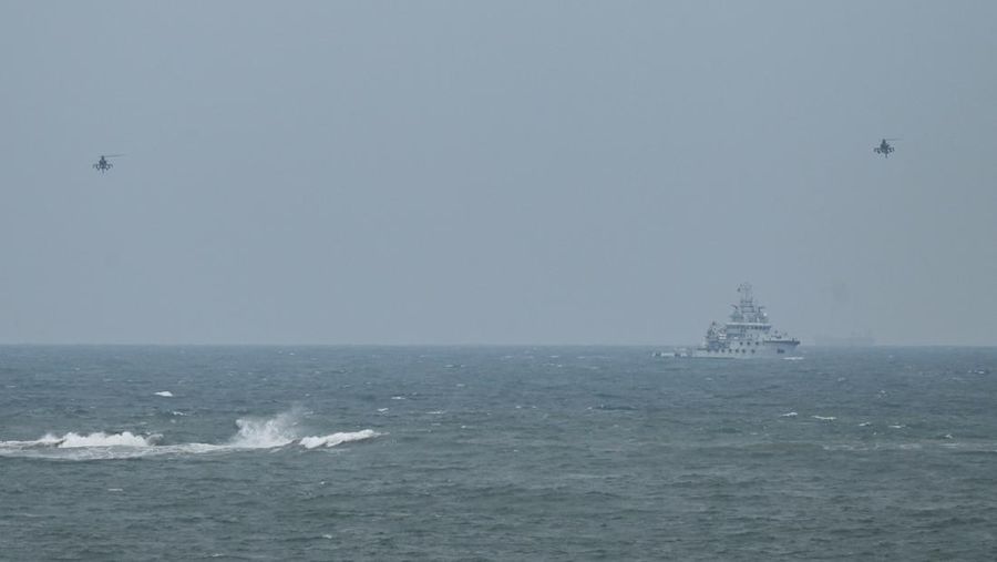 Dua helikopter militer China terbang melewati kapal tunda Angkatan Laut PLA, seperti yang terlihat dari pulau Pingtan, titik terdekat ke Taiwan, di provinsi Fujian tenggara China pada 7 April 2023. (GREG BAKER/AFP via Getty Images)
