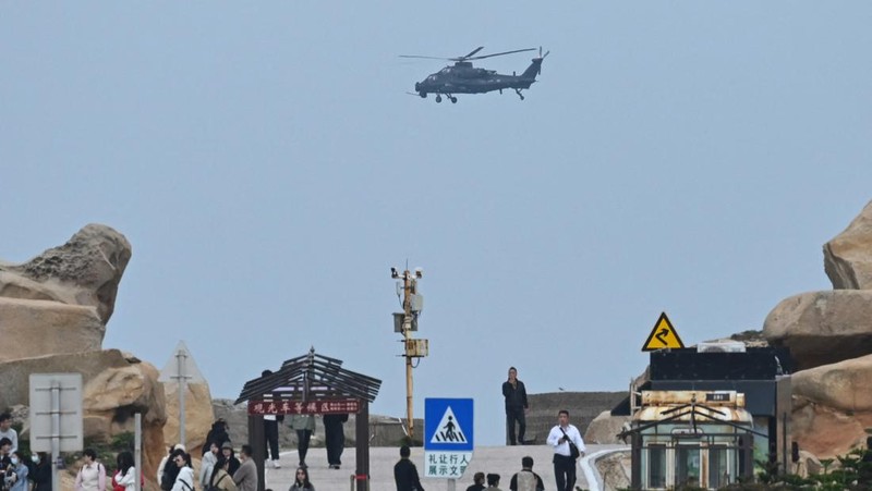 Helikopter militer China terbang melewati turis di titik pandang di atas Selat Taiwan, di pulau Pingtan, titik terdekat ke Taiwan, di provinsi Fujian tenggara China pada 7 April 2023. (GREG BAKER/AFP via Getty Images)