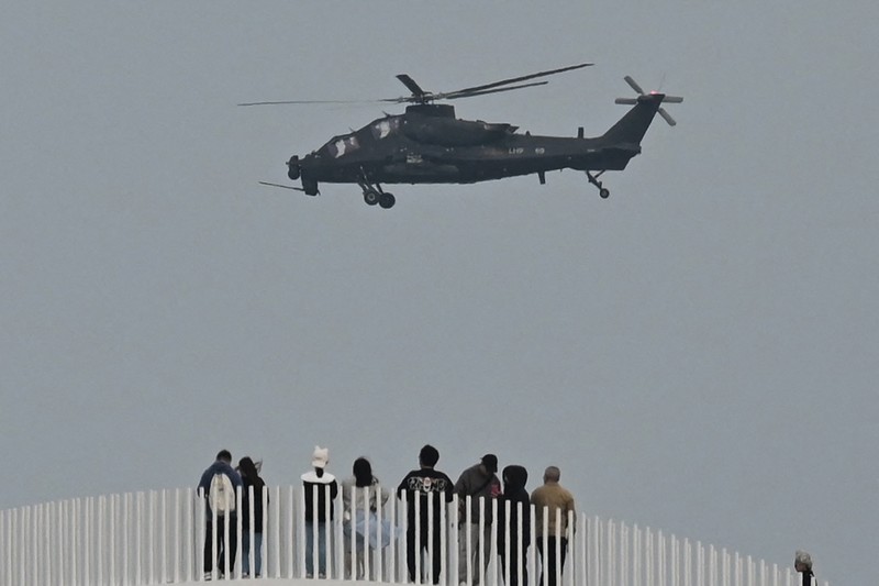 Helikopter militer China terbang melewati turis di titik pandang di atas Selat Taiwan, di pulau Pingtan, titik terdekat ke Taiwan, di provinsi Fujian tenggara China pada 7 April 2023. Helikopter militer China terbang melewati turis di titik pandang di atas Selat Taiwan, di pulau Pingtan, titik terdekat ke Taiwan, di provinsi Fujian tenggara China pada 7 April 2023. (GREG BAKER/AFP via Getty Images)
