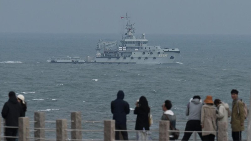 Helikopter militer China terbang melewati turis di titik pandang di atas Selat Taiwan, di pulau Pingtan, titik terdekat ke Taiwan, di provinsi Fujian tenggara China pada 7 April 2023. (GREG BAKER/AFP via Getty Images)