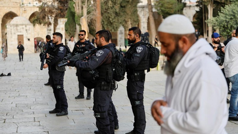 Pengunjung Yahudi berjalan melewati orang-orang yang membaca Alquran, di kompleks Masjid Al-Aqsa, yang dikenal umat Islam sebagai Tempat Suci Mulia dan bagi orang Yahudi sebagai Temple Mount, sementara ketegangan muncul selama bentrokan di Kota Tua Yerusalem, 9 April 2023. (REUTERS/Ammar Awad)