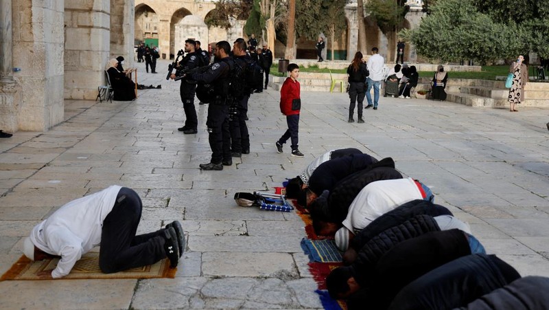 Pengunjung Yahudi berjalan melewati orang-orang yang membaca Alquran, di kompleks Masjid Al-Aqsa, yang dikenal umat Islam sebagai Tempat Suci Mulia dan bagi orang Yahudi sebagai Temple Mount, sementara ketegangan muncul selama bentrokan di Kota Tua Yerusalem, 9 April 2023. (REUTERS/Ammar Awad)