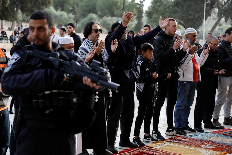 Pengunjung Yahudi berjalan melewati orang-orang yang membaca Alquran, di kompleks Masjid Al-Aqsa, yang dikenal umat Islam sebagai Tempat Suci Mulia dan bagi orang Yahudi sebagai Temple Mount, sementara ketegangan muncul selama bentrokan di Kota Tua Yerusalem, 9 April 2023. (REUTERS/Ammar Awad)