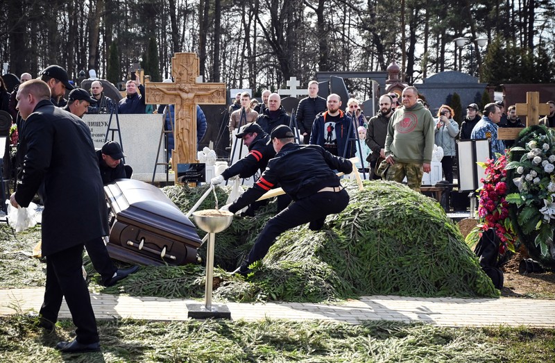 Para karyawan mengubur peti mati berisi jenazah blogger militer Vladlen Tatarsky (nama asli Maxim Fomin) selama pemakaman di Moskow pada 8 April 2023. - Ratusan pendukung hadir pada 8 April 2023, untuk pemakaman seorang petinggi Rusia blogger militer tewas dalam serangan bom. (ALEXANDER NEMENOV/AFP via Getty Images)
