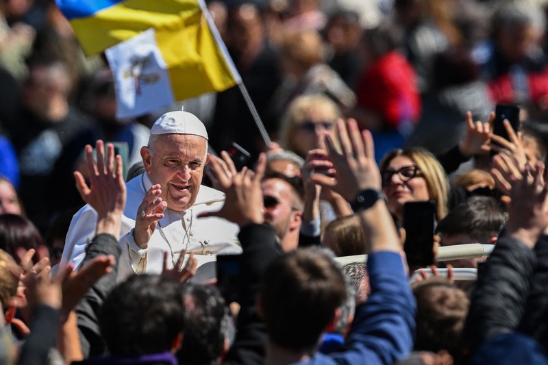 Paus Fransiskus melambai dari loggia Basilika Santo Petrus yang menghadap ke alun-alun Santo Petrus, setelah menyampaikan berkat Paskah Urbi et Orbi pada 9 April 2023 di Vatikan. (ANDREAS SOLARO/AFP via Getty Images)