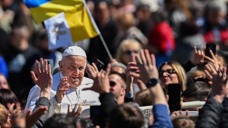 Paus Fransiskus melambai dari loggia Basilika Santo Petrus yang menghadap ke alun-alun Santo Petrus, setelah menyampaikan berkat Paskah Urbi et Orbi pada 9 April 2023 di Vatikan. (ANDREAS SOLARO/AFP via Getty Images)